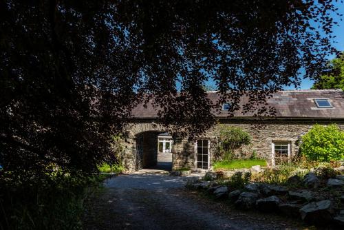 a stone building with an archway in front of it at Ardnavaha House - Poolside Cottages in Clonakilty
