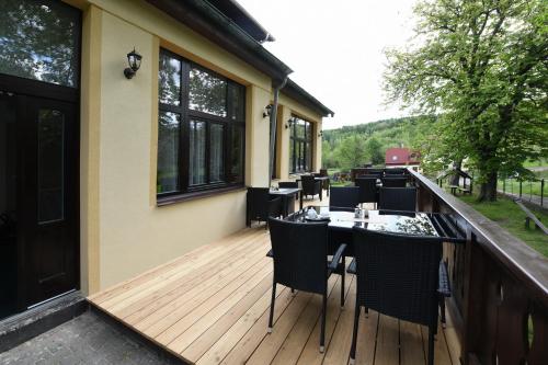 a deck with a table and chairs on it at Hotel Švýcarský dům in Sněžnik