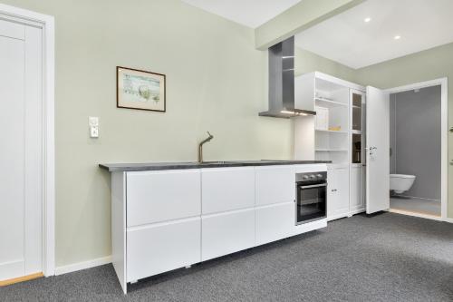 una cocina con armarios blancos y fregadero en Central Studio Apartment Apt 202, en Stavanger