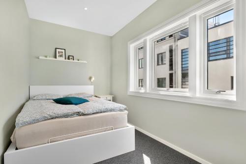a white bedroom with a bed and two windows at Central Studio Apartment Apt 202 in Stavanger