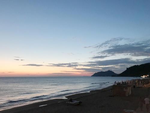 a beach with people and the ocean at sunset at Nereides Apartments in Agios Gordios