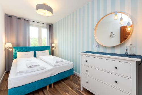 a blue and white bedroom with a bed and a mirror at Apartamenty Usteckie Wczasowa in Ustka