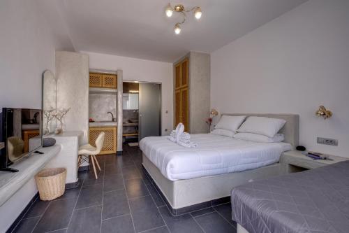 Habitación de hotel con 2 camas y sala de estar. en Beach Houses Santorini en Kamari