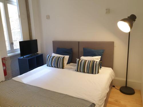 ポルトにあるCitybreak-Apartments Caldeireirosのベッドルーム1室(枕2つ、ランプ付)