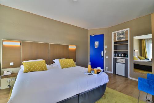 a bedroom with a large white bed with yellow pillows at Hotel Amiraute in Cannes