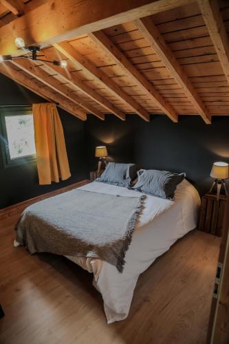 - un grand lit dans une chambre dotée de plafonds en bois dans l'établissement Le petit coin de Jeanne et Marcel chalet de vacances La Bresse, à La Bresse