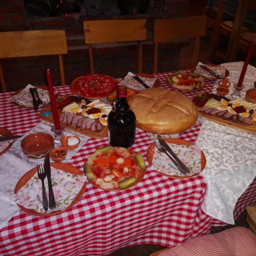 a table with a red and white checkered table cloth with food and wine at Etno Konak Angela in Kalna