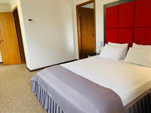 a bedroom with a large white bed with a red headboard at Green Park Hotel & SPA in Truskavets