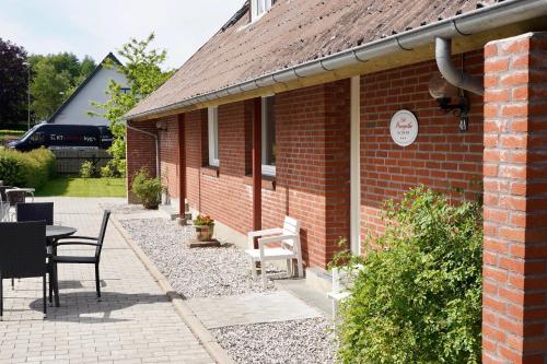 a brick house with a patio and a table and chairs at Lille Margrethe in Gadbjerg