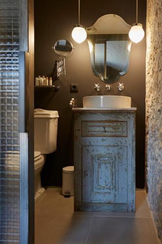 a bathroom with a sink and a toilet and a mirror at Llimona Suites - Adults Only in Corsá