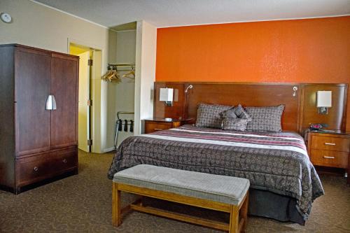 een slaapkamer met een groot bed met een oranje muur bij America's Best Inn and Suites Emporia in Emporia