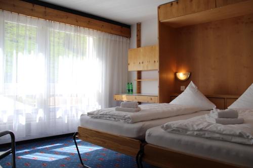 two beds in a room with a window at Hotel Aurora in Andermatt