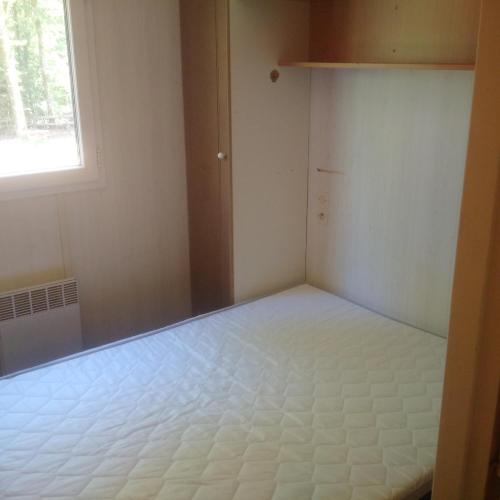 um quarto vazio com uma cama e uma janela em mobilhome lac de vassiviere em Faux-la-Montagne