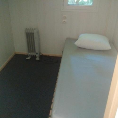 um pequeno quarto com uma cama e uma janela em mobilhome lac de vassiviere em Faux-la-Montagne