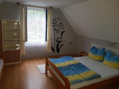 a bedroom with a bed with blue and yellow pillows at Áron Apartman in Badacsonytomaj