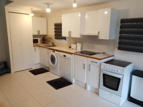 une cuisine avec des armoires blanches et une laveuse et une sécheuse dans l'établissement Modern Bright House, à Saint-Germain-en-Laye