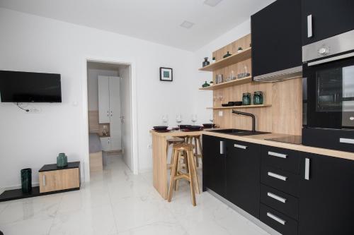 a kitchen with black cabinets and a counter top at Kuće za odmor -Japin breg in Ðurđevac