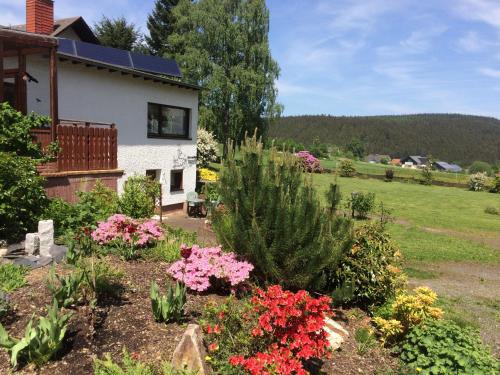a garden in front of a house with flowers at Haus am Wald - Urlaub am Nationalpark in Langweiler
