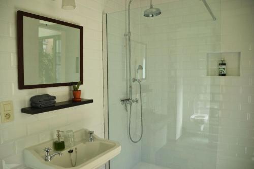 baño blanco con ducha y lavamanos en Quiet apartment in Antwerp near parc - B&B InterMezzo - business & leisure, en Amberes