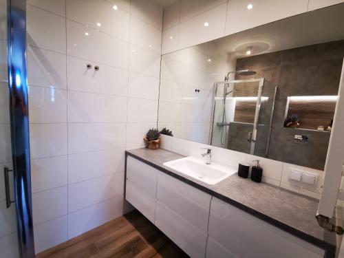 een witte badkamer met een wastafel en een spiegel bij Walowa Tower Apartments in Gdańsk