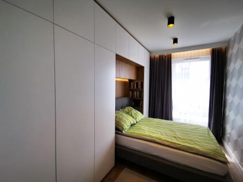 een slaapkamer met een bed met een raam en een stoel bij het raam bij Walowa Tower Apartments in Gdańsk