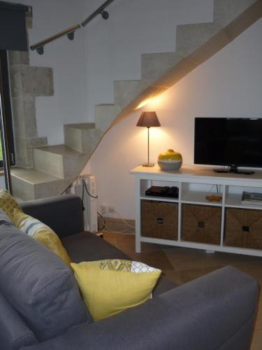 a living room with a couch and a tv at Hexagonal Tower for 2 with shared pool in Semur-en-Auxois
