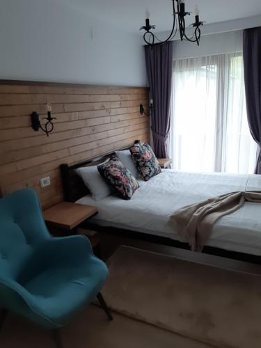a bedroom with a bed and a blue chair at Chalet Mugure de Brad in Fundu Moldovei