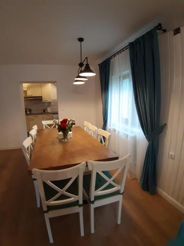 a dining room table with white chairs and a large window at Chalet Mugure de Brad in Fundu Moldovei