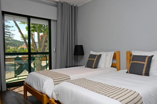 two beds in a hotel room with a balcony at HI Setubal - Pousada de Juventude - CASA DO LARGO in Setúbal
