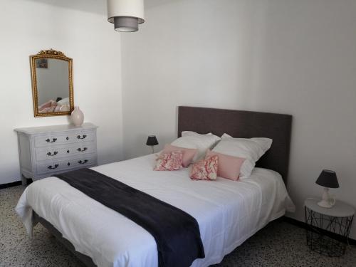 une chambre avec un grand lit blanc avec des oreillers roses dans l'établissement BEL APPARTEMENT SPACIEUX CENTRE VILLE UZES T3, à Uzès