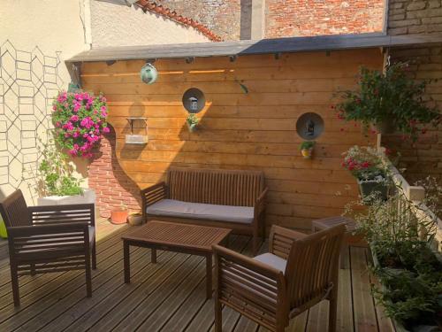 a wooden patio with two chairs and a table and a wall at le patio de l'oustal in Gimont
