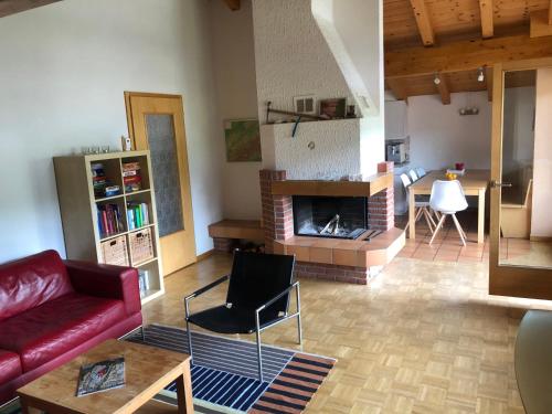 a living room with a red couch and a fireplace at Casa Spel Mir in Disentis