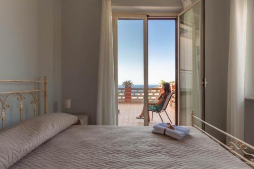 una mujer sentada en una silla en una habitación con ventana en San Martino Holiday Apartments en Capo dʼOrlando