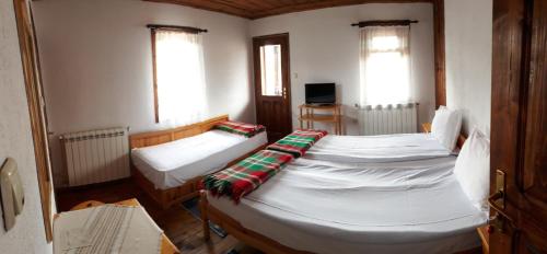 a room with two beds and a tv and two windows at Sarafova Guest House in Koprivshtitsa