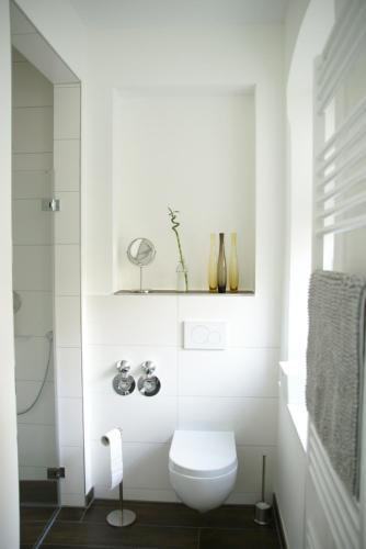 a white bathroom with a toilet and a shower at Alte Schule Wachenheim im Zellertal in Wachenheim