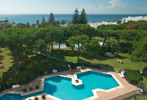 een uitzicht over een zwembad met de oceaan op de achtergrond bij Apartamento Playas del Duque - Puerto Banús - Marbella in Marbella