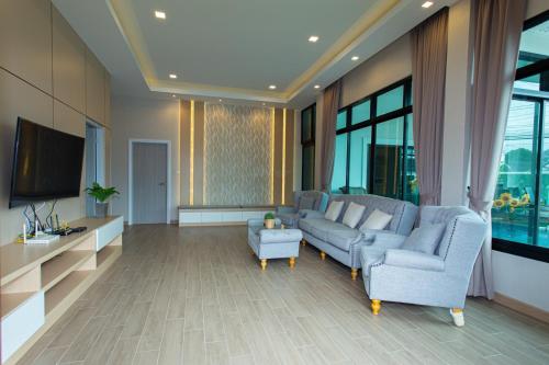 a living room with a couch and two chairs and a tv at Uzeason Poolvilla Sattahip in Sattahip