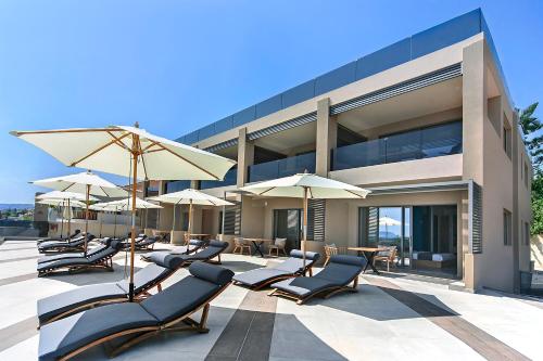 a group of chairs and umbrellas in front of a building at Lilium Luxury Suites in Agia Marina Nea Kydonias