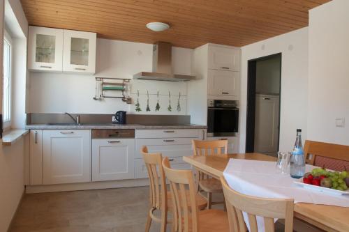 a kitchen with white cabinets and a table and chairs at Ferienhaus An der Hilb in Stetten am Kalten Markt