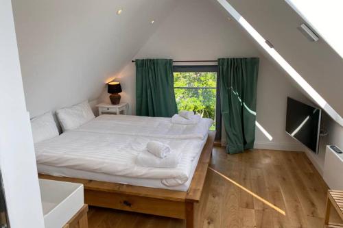 a bedroom with a white bed with green curtains at Cottage@Baltic-Chalets in Kalkhorst