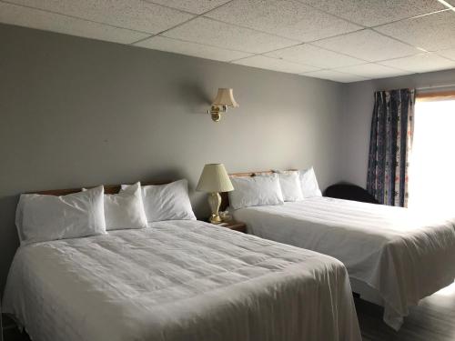 um quarto com 2 camas com lençóis brancos e uma janela em Hotel-Motel Le Panorama em Perce