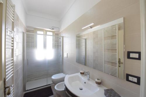a white bathroom with a toilet and a sink at Casa Vacanze TITINA HOME in Montalbano
