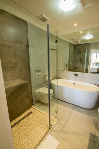 a bathroom with a shower and a tub and a toilet at Laguna Grove 15 3 bedroom apartment in Knysna