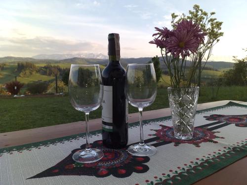 a bottle of wine and two wine glasses on a table at Domek na wzgórzu in Łapsze Niżne