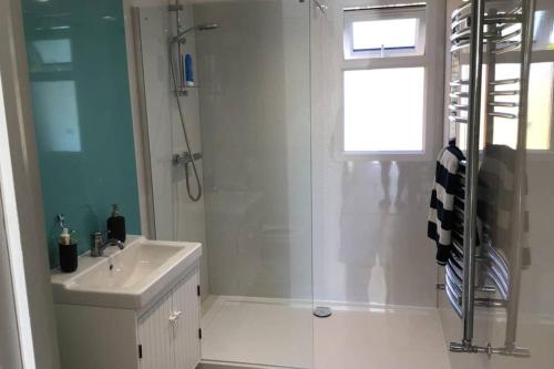 een witte badkamer met een douche en een wastafel bij Mudeford Mews in Mudeford