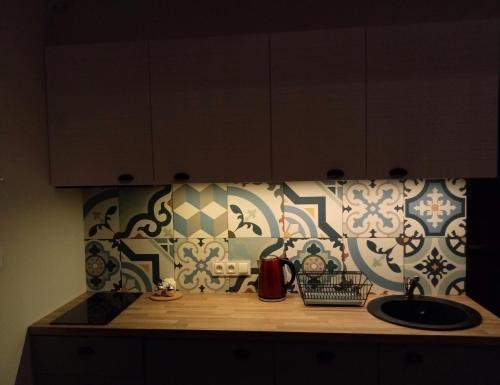 a kitchen counter with a sink and a tile wall at Domek Mierzeja in Kąty Rybackie
