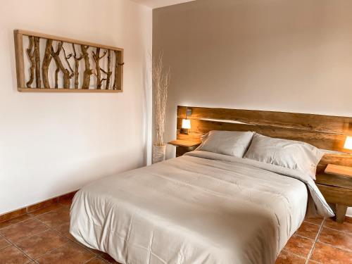 a bedroom with a white bed with a wooden headboard at Casa As Fontes in Porqueirós