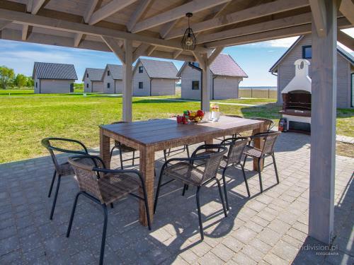 een houten tafel en stoelen op een patio met een grill bij Słoneczna Przystań in Dziwnówek