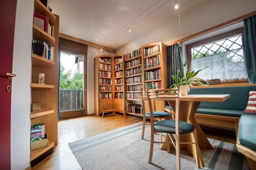 a home library with a table and chairs and bookshelves at Pension Fellis in Vols am Schlern