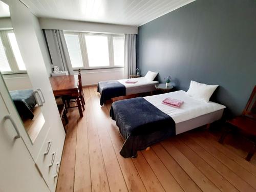 una habitación de hotel con 2 camas y un piano en Center Hostel Kaatrahovi, en Lieksa